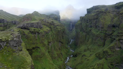 Smooth-Drone-footage-flying-through-deep-Icelandic-Mulagljufur-canyon,-with-dramatic-Hangandifoss-waterfall-at-the-end-of-the-canyon,-with-river-in-Southern-Region,-Iceland