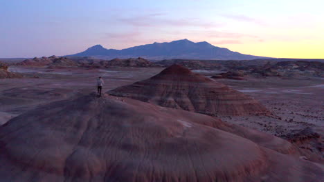 Drone-Volando-Sobre-El-Hombre-Caminando-En-Formaciones-Rocosas-De-Colores-En-La-Estación-De-Investigación-Del-Desierto-De-Marte-En-Utah,-Estados-Unidos