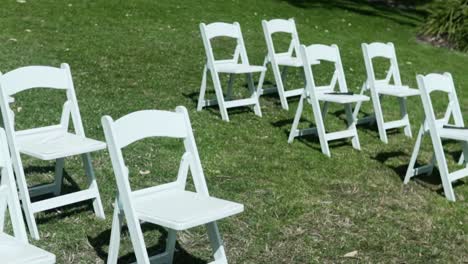 White-Folding-Chairs-On-Meadow-Landscape-At-Outdoor-Wedding-During-Sunny-Day