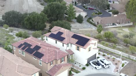 Two-neighborhood-houses-with-solar-panels,-renewable-energy-concept,-Tesla-Model-3-in-driveway,-aerial