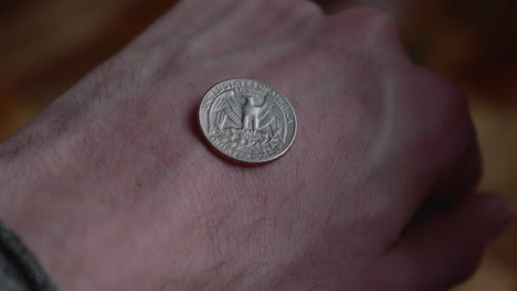 Mann-Zeigt-Eine-Vierteldollarmünze-Auf-Dem-Handrücken-Der-Faust