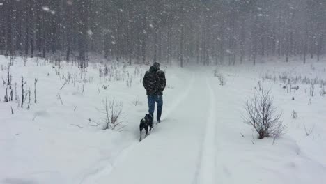 A-man-with-a-camouflage-jacket-walks-on-a-snowy-path-during-a-snowstorm