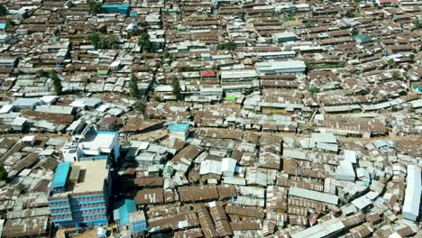 Aerial-tilt-up-shot-of-crowded-urban-slum-area-in-Kibera-and-modern-skyline-of-Nairobi-in-background-during-sunlight