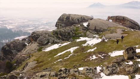 Male-and-female-runners-running-on-a-mountain-in-winter-drone-shot
