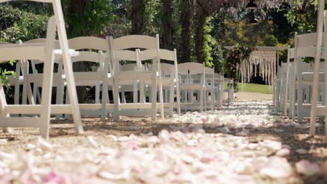 Hochzeitsgang-Im-Freien---Weiße-Klappstühle-Mit-Blütenblättern-Auf-Dem-Boden-Für-Die-Hochzeitszeremonie---Selektiver-Fokus