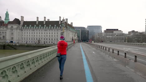 Mujeres-Británicas-Caminando-A-Lo-Largo-De-Un-Puente-De-Westminster-Vacío-Mientras-Pasan-Una-Motocicleta-De-La-Policía-Y-Un-Autobús-De-Dos-Pisos