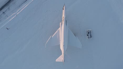 Top-down-aerial-of-Icelandic-fighter-jet-covered-in-winter-snow,-Keflavik