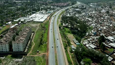 Aerial-flyover-road-with-driving-cars-surrounded-by-poor-urban-slums-in-Nairobi-during-sunny-day