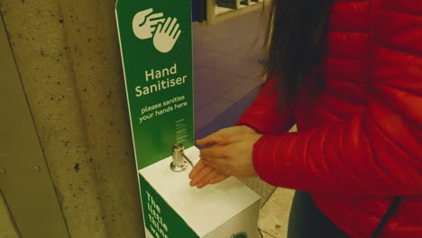4k,-slow-motion-shot-of-young-woman-using-hand-sanitizer-before-entering-the-underground-station-in-London
