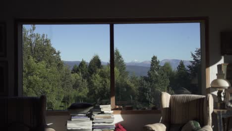 Amazing-window-view-of-big-snowy-mountain-and-trees-vegetation-from-Cozy-living-room-with-sofas,-in-elegant-house-Slow-Motion-and-60fps
