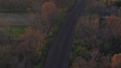 Overhead-view-of-train-tracks-in-small-town-in-Autumn-with-tilt-up