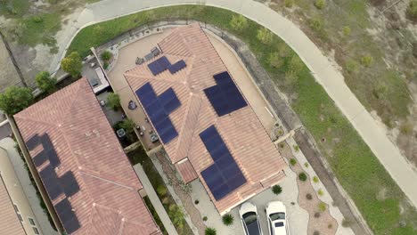 Solar-Panels-on-roof-of-two-houses,-aerial-rising-with-Tesla-in-driveway
