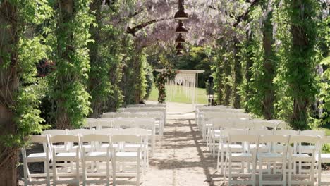 White-Chairs-Stand-In-The-Rows-Before-Wedding-Altar---Wedding-Ceremony-In-A-Beautiful-Garden---approach