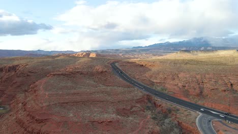 Beautiful-scenic-aerial-view-of-Utah-red-rocky-terrain-with-vehicles-in-road