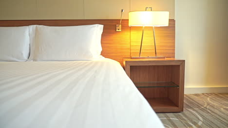 Slow-slide-left-on-made-up-white-king-size-bed-in-the-hotel-night-time-lamp-light-on