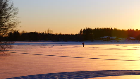 Reveal-shot-of-one-person-exercising-cross-country-skiing-in-winter-day-at-sunset,-Finland