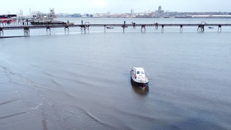 Aerial-leisure-sail-boat-moored-on-sandy-Liverpool-city-docks-industrial-coastline-orbit-right
