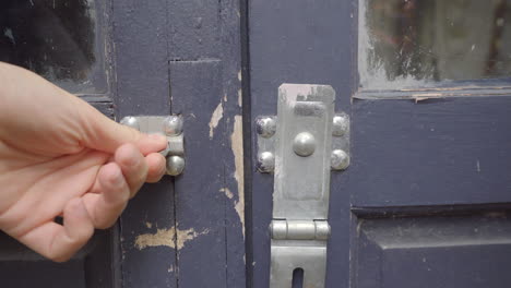 Man-Unlocks-Padlock-Of-A-Blue-Door