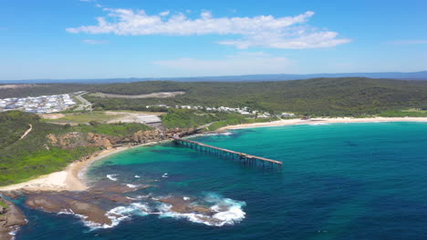 Catherine-Hill-Bay-pier-on-NSW-Australia-coastline,-aerial-reveal-over-bay