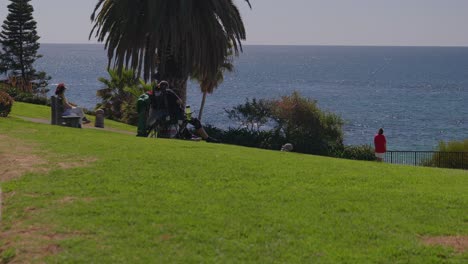 People-sitting-and-enjoying-the-scenic-ocean-view,-at-a-hillside-park,-in-Laguna-Beach-California