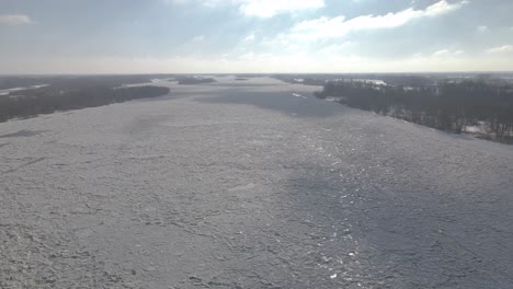Aerial-wide-shot-of-the-great-river-covered-with-ice-and-snow-during-strong-winter-in-Europe