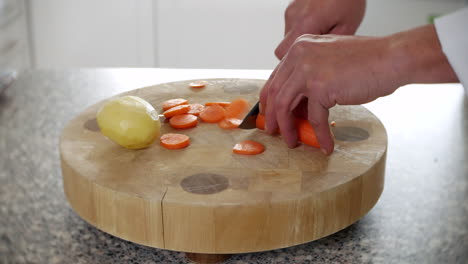 Ein-Koch-Schneidet-Karotten-In-Einer-Küche-Auf-Einem-Schneidebrett-Mit-Einem-Messer