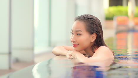 Close--up-a-beautiful-flawless-woman-is-poised-on-the-edge-of-a-luxury-infinity-edge-swimming-pool