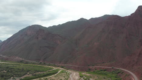 Aerial---Highway-and-mountains,-Cafayate,-Argentina,-wide-lowering-shot