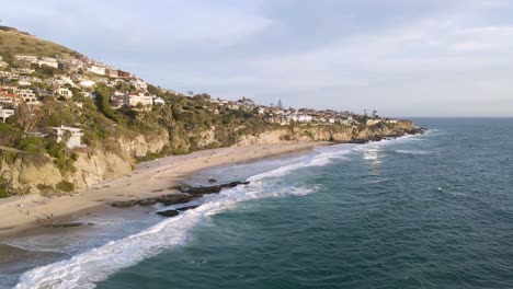 Sunset-and-calm-sea-at-thousand-steps-beach-in-Laguna-California,-Drone-wide-panning-shot