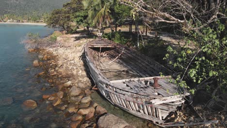 Aerial-view,-spoiled-wooden-boat-on-the-shore-of-the-sea