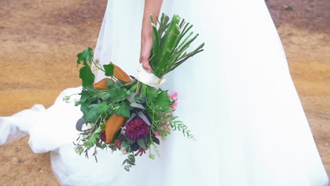 Bride-In-Traditional-Bridal-Gown-Holding-Her-Colorful-Bouquet-Of-Fresh-Flowers-During-Outdoor-Wedding-Ceremony