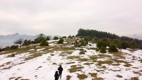 Atletas-Corriendo-En-Una-Montaña-Sobre-La-Nieve-En-Un-Tiro-De-Drone-De-Invierno