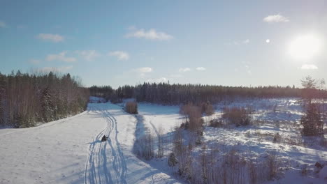 Person-driving-away-in-ATV-on-extreme-winter-terrain-in-aerial-view