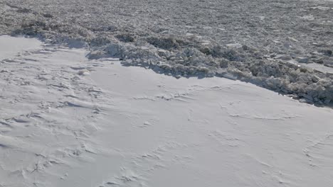 Luftaufnahme-Des-Vollständig-Zugefrorenen-Flusses,-Der-Im-Starken-Winter-Mit-Eis-Und-Schnee-Bedeckt-Ist