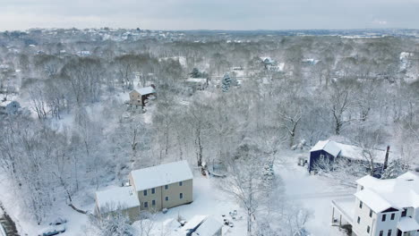 Drone-footage-of-trees-and-houses-in-a-residential-neighborhood-in-Hingham-MA-after-snowstorm,-Slow-forward-motion