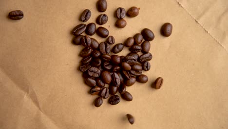 Coffee-beans-drop-from-above-on-old-paper-slow-motion