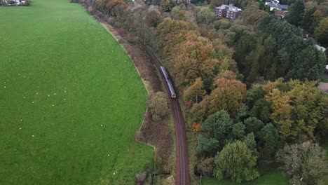 Tilt-up-reveal-of-train-crossing-countryside-and-Scottish-urban-residential-area