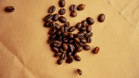Coffee-beans-drop-from-above-on-old-paper-slow-motion-vintage-look
