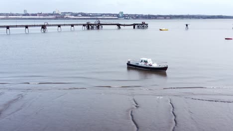Aerial-leisure-sail-boat-moored-on-sandy-Liverpool-city-docks-coastline-low-orbit-right