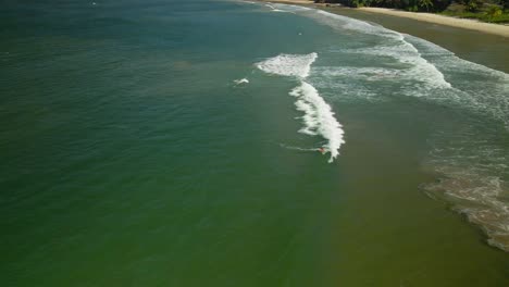 Aerial-view-of-a-surfer-paddling-and-misses-a-wave-in-Las-Cuevas-Bay,-Trinidad