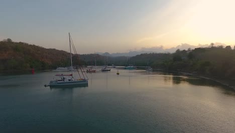 Evening-calm,-subtle-golden-sunset-over-yachts-in-secluded-bay-aerial-view