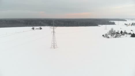 Langsame-Antenne-über-Winterlichen-Feldern-Mit-Einem-Telegrafenturm-Auf-Einem-Feld
