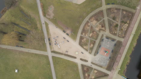 Top-down-overview-of-children-playing-in-suburban-park---drone-lifting-up