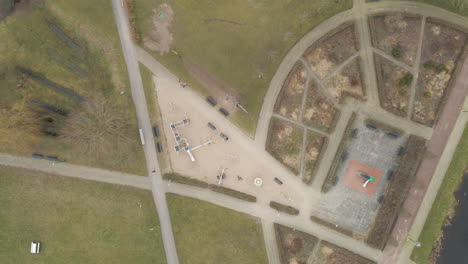 Top-down-overview-of-children-playing-in-suburban-park---drone-setting-down