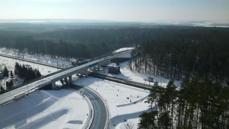 Panoramic-View-Of-Railway-Road-And-Flyover-Through-Forest-Landscape-During-Winter-In-Rakowice,-Krakow,-Poland---aerial-drone-shot