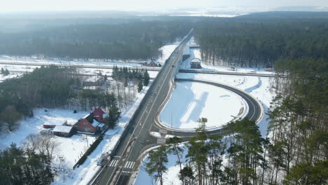 Car-Travels-On-The-Flyover-Bridge-With-Forest-And-Curve-Road-During-Winter-Season-In-Rakowice,-Krakow,-Poland