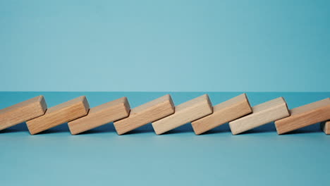 Domino-effect,-row-of-wooden-domino-falling-down-with-light-blue-background