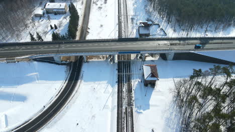 Car-Drives-In-The-Flyover-Bridge-Surrounded-By-Green-Forest-And-Houses-In-Snowy-Field-In-Rakowice,-Krakow,-Poland