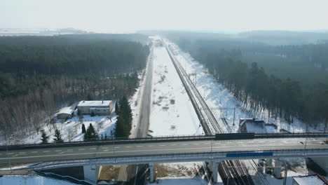 Leerer-Viadukt,-Der-Eine-Andere-Schwarze-Straße-Und-Drei-Gleise-Einer-Eisenbahn-In-Der-Nähe-Eines-Bahnhofs-Zwischen-Den-Bäumen-In-Einer-Winterlandschaft-Nera-Rakowice-überquert