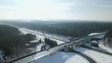 Scenic-aerial-orbit-shot-of-cars-driving-along-snowy-highway-bridge-in-winter